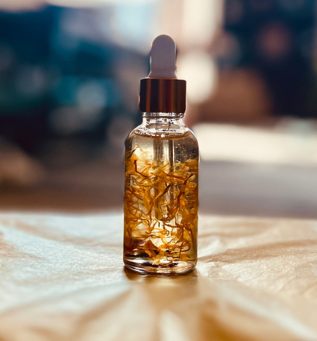 Glass dropper bottle with botanical oil infusion in golden sunlight